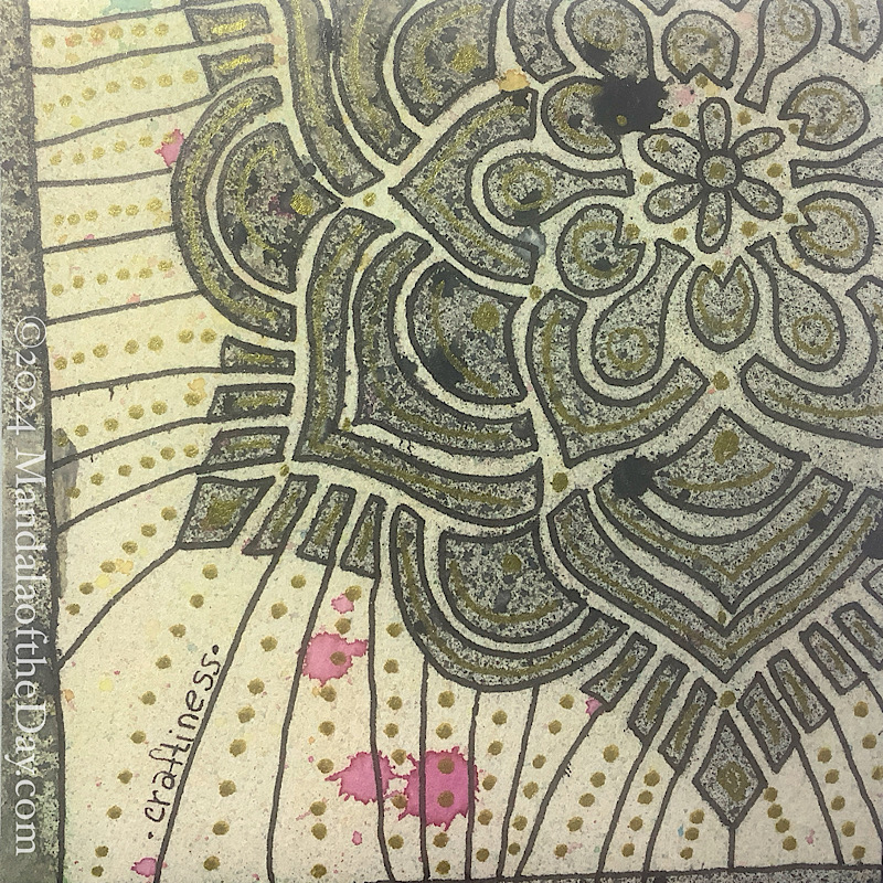 MotD 24-247 Craftiness — After. textured abstract background in off-white with micro dots of different colors. In splattered black watercolors is a partial stenciled mandala, with the center in the upper right. on top I used metallic black ink to outlined the stenciled mandala. within each section I added a metallic gold element: arched line, dot, or circle. black lines are drawn from the outer elements of the mandala out to the edge. in between the black lines is a line of gold dots.