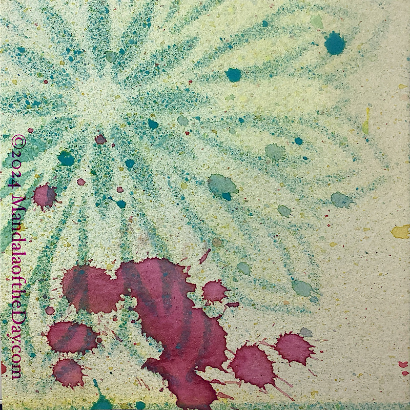 MotD 24-256 Thrift — Before. textured abstract background of pale yellow with microdots of different colors. on top is a partial textured stencil mandala in mostly blue/green colors, the center of it towards the upper left corner. In the bottom left corner are some blobs of magenta ink.